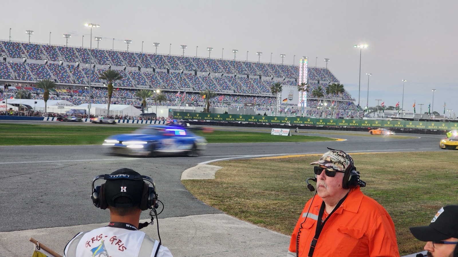 Night racing at Daytona with a corner marshal in orange watching cars pass